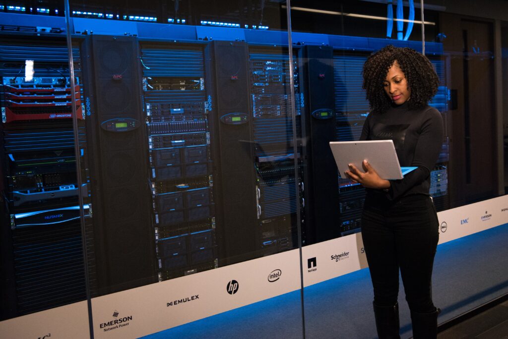 Woman looking at computer next to a server room
